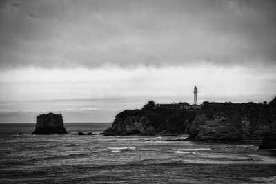 Lighthouse by sea against sky