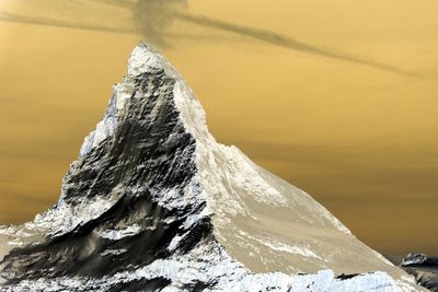 Snow on rock against sky during sunset