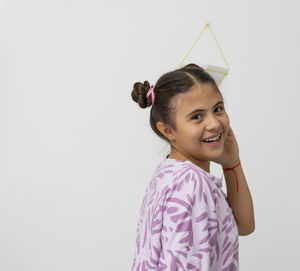 Portrait of smiling girl standing against white background