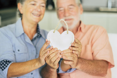 Senior couple holding heart shape decoration while sitting at home