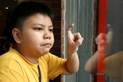 Boy gesturing while looking through window in cafe