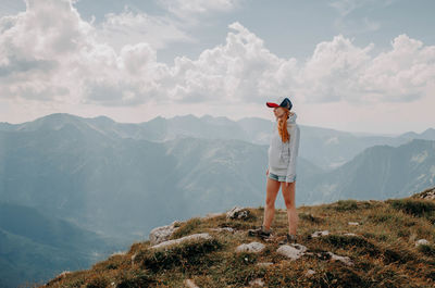 Rear view of woman standing on mountain against sky