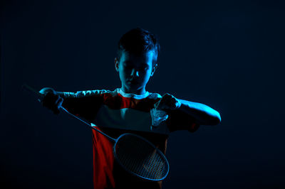 Boy holding badminton against black background
