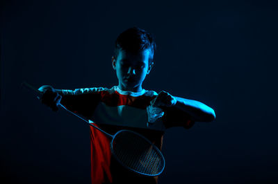 Full length of boy holding blue while standing against black background