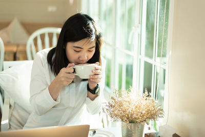 Young woman drinking coffee in cup