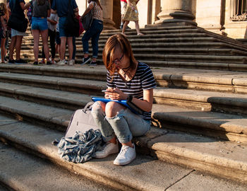 Full length of teenage girl using mobile phone while sitting on steps