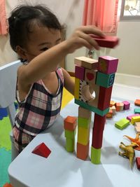 Cute girl playing with toy blocks at home