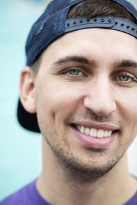 Close-up portrait of smiling confident man wearing cap