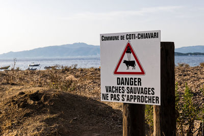 Information sign on beach against sky