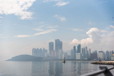 Sea and buildings in city against sky