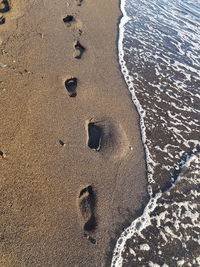 High angle view of footprints on sand at beach