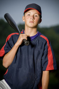 Portrait of a baseball player holding his bat wearing a warm up jacket