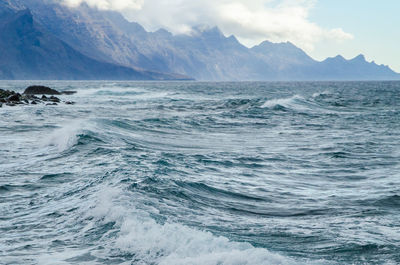 Idyllic shot of sea and mountains against sky