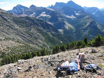 Rear view of men sitting on landscape against mountains