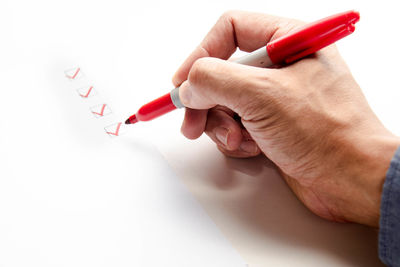 Close-up of hand holding paper over white background