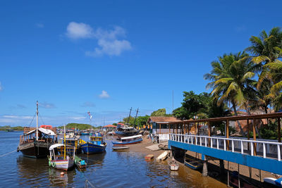 Boats moored in sea against blue sky