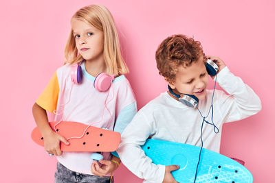 Cheerful sibling wearing headphones against colored background
