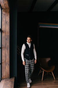 Portrait of young man standing against wall at night