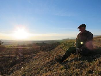 Man sitting on landscape against sky