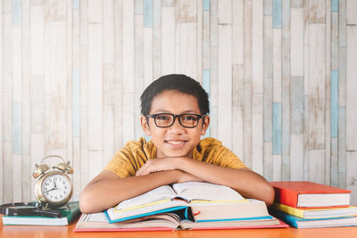 Portrait of teenage boy with open book on table