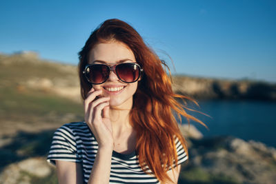 Portrait of young woman wearing sunglasses against sky