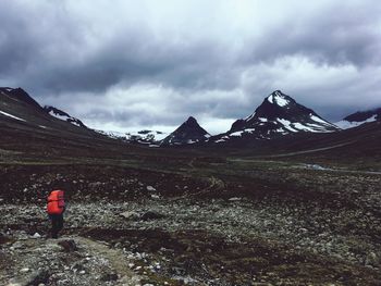 Rear view of person on snowcapped mountain against sky