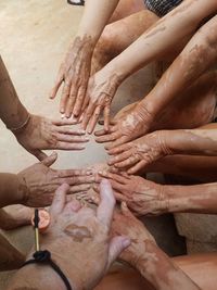 High angle view of muddy hands huddling outdoors