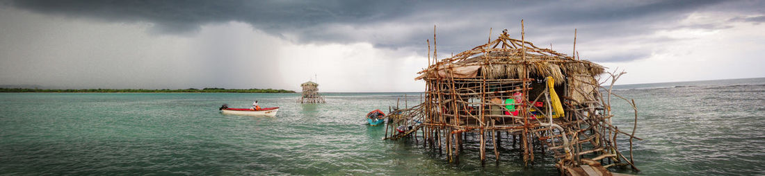 People in sea against cloudy sky