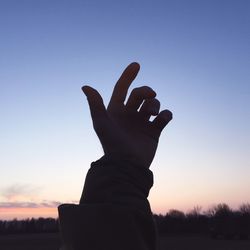 Low angle view of silhouette hand against sky during sunset