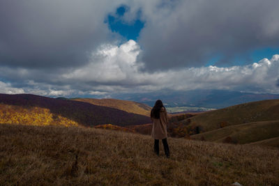 Rear view of woman walking on field against sky