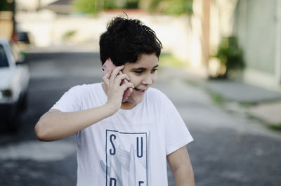 Teenage boy outdoors talking on the phone and laughing 