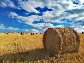 Hay bales on field against sky