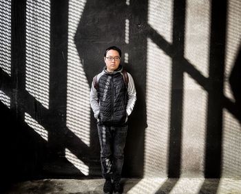 Portrait of young man standing against wall