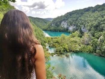 Rear view of woman looking at lake against mountains