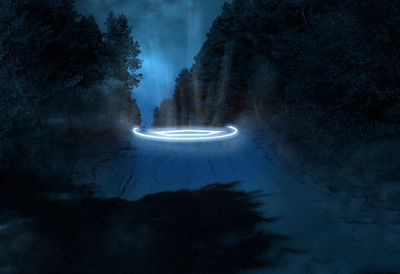 Road in the forest at night with glowing neon elements, pine trees on the sides. abstract background