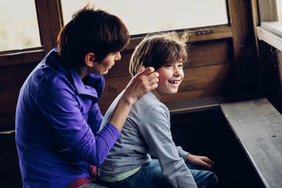 Happy mother and daughter sitting in log cabin