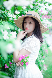 Side view portrait of beautiful woman standing by flowers at park