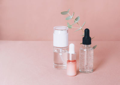 Glass bottles on a shiny pink fabric background. serum or essential aroma oil,  massage. 