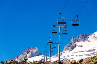 Low angle view of ski lift against clear blue sky