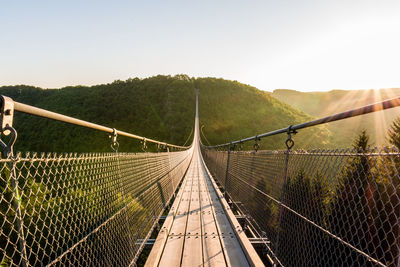 Suspension bridge and mountain against sky