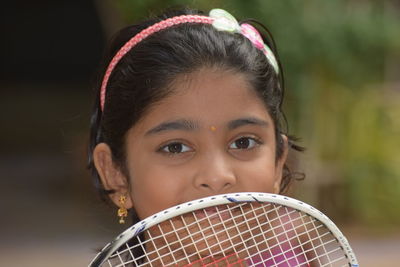 Close-up portrait of girl with badminton racket