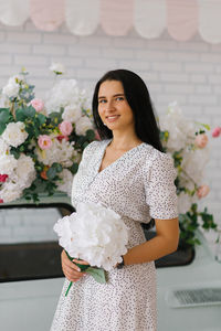 Cute girl holds a bouquet of white hydrangeas in her hands and smiles happily