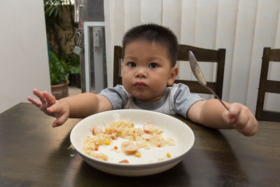 Portrait of cute boy sitting on table at home