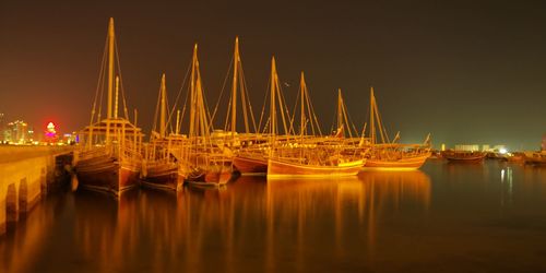 Sailboats moored on sea against sky at night