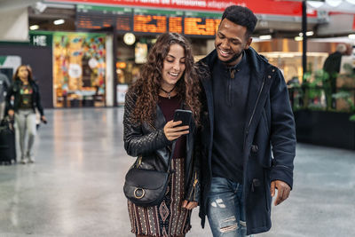 Smiling couple looking at phone while walking outdoors