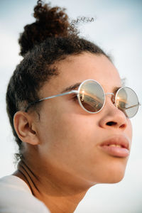 Close-up of young woman wearing sunglasses during sunset
