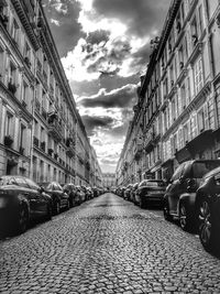 Cars on street amidst buildings in city against sky