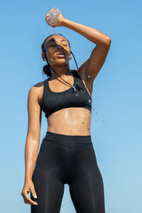 Portrait of young woman standing against blue sky