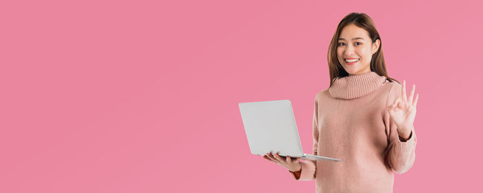 Woman standing against pink background