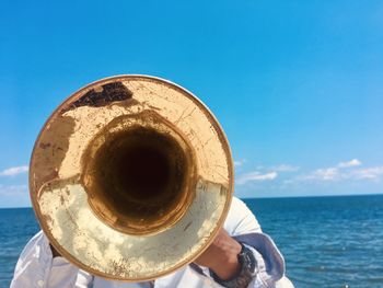 Low angle view of person holding blue sea against sky